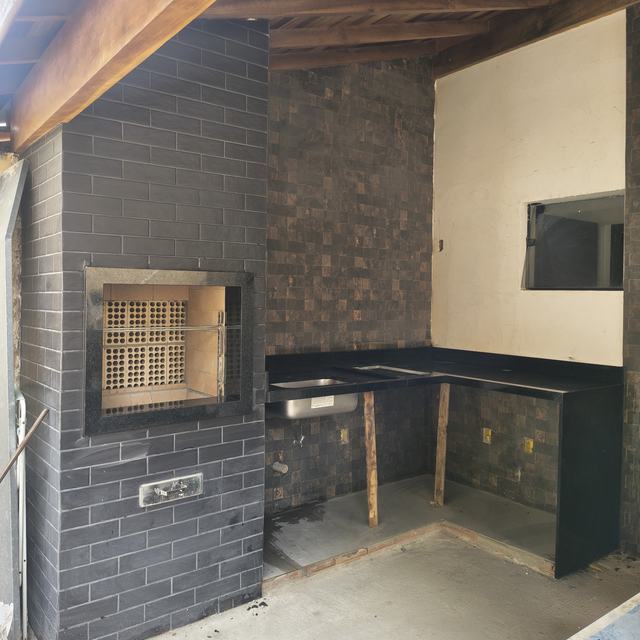 Área gourmet com bancada em L de granito preto e churrasqueira